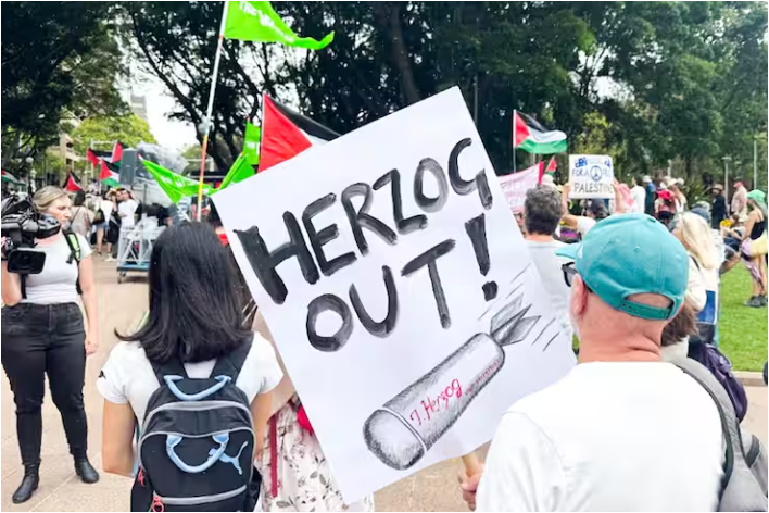 متظاهرون يرفعون لافتات تندد بزيارة الرئيس الإسرائيلي إسحق هرتسوج في أستراليا