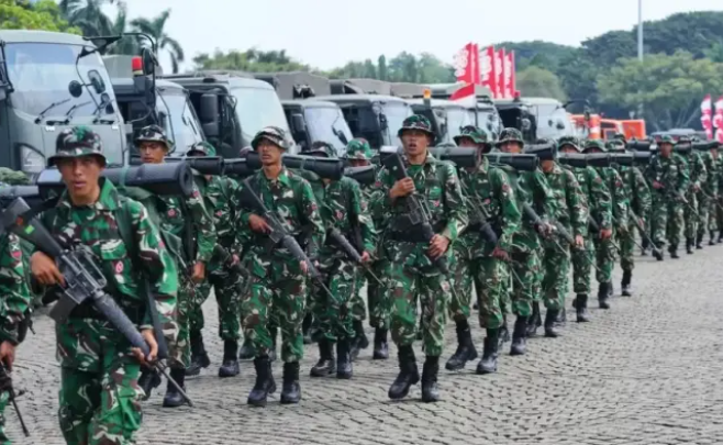 عناصر من الجيش الإندونيسي يسيرون في عرض عسكري وهم يحملون أسلحة فردية ويرتدون الزي المموه