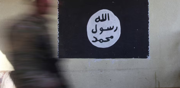 جندي يمر أمام راية تنظيم الدولة الإسلامية في صورة أرشيفية