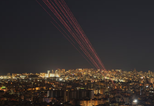 خطوط صواريخ في السماء فوق مدينة ليلاً