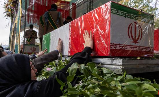 مشيعون يلمسون نعشًا ملفوفًا بعلم إيران خلال مراسم تشييع قتلى الحرب