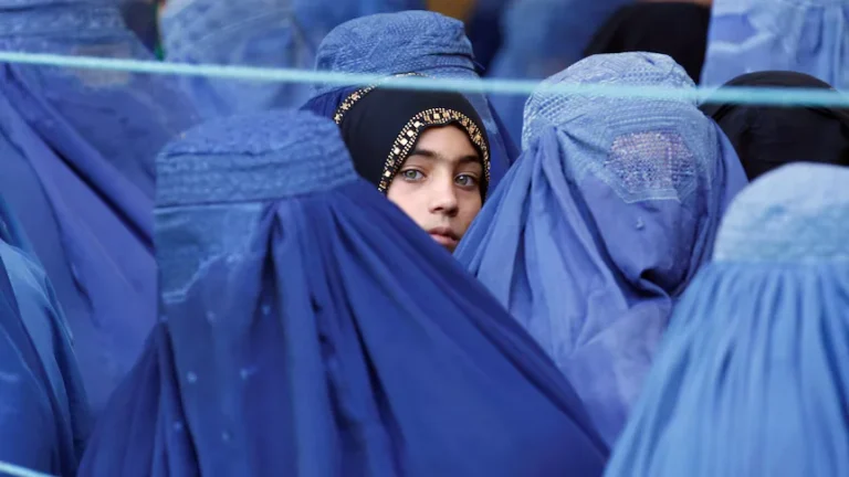 امرأة أفغانية ترتدي برقع أزرق تنظر من خلفه