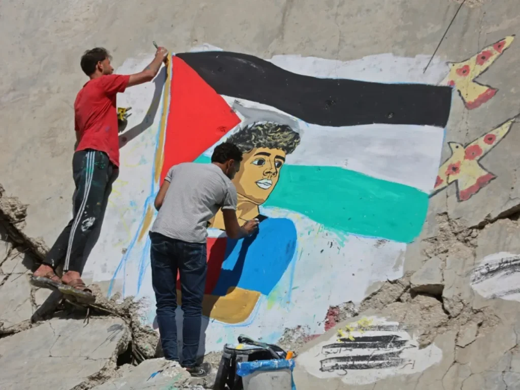 فنانون يرسمون جدارية للعلم الفلسطيني وسط أنقاض في قطاع غزة - Artists paint a Palestinian flag mural amid rubble in Gaza